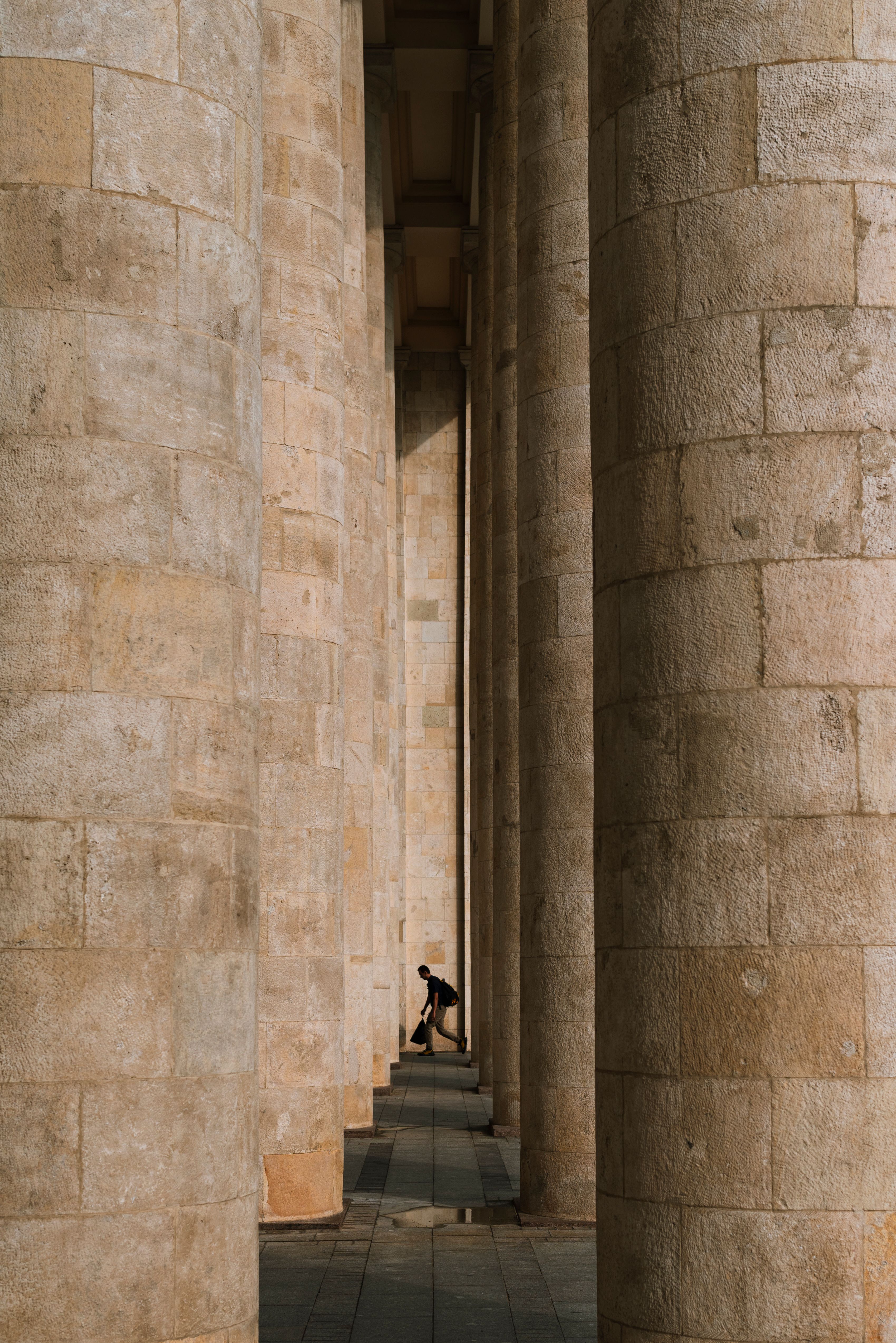Giant stone columns creating dramatic shadows in Moscow, capturing a silhouette of a person.