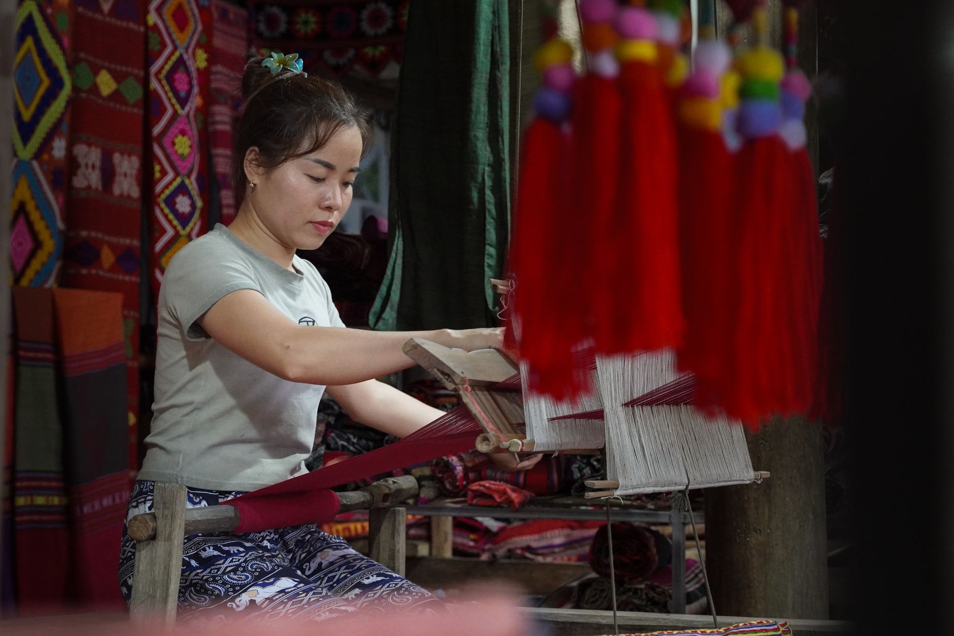 Young Muong woman weaving vibrant textiles in Thanh Hoรก, Vietnam.