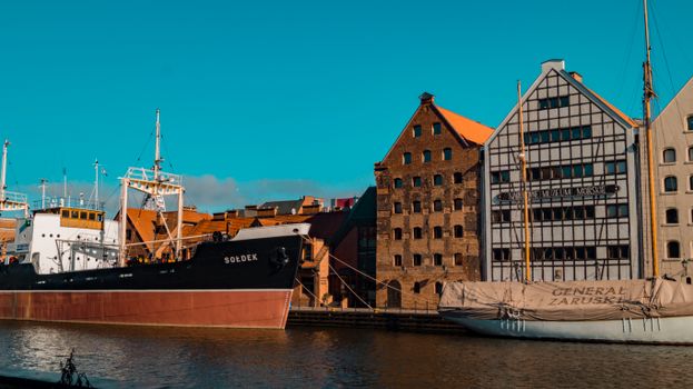 Vessels docked at Gdańsk's Maritime Museum under a clear sky, showcasing historic architecture.