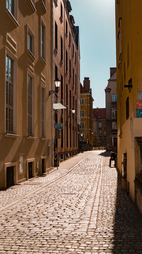 Free Quaint cobblestone street lined with historic buildings in Gdańsk, Poland, on a sunny day. Stock Photo
