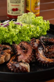 Delicious grilled octopus served with fresh lettuce and spicy condiment.