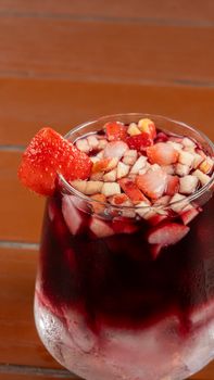 Chilled glass of fruity sangria, topped with chopped strawberries, perfect for summer refreshment.