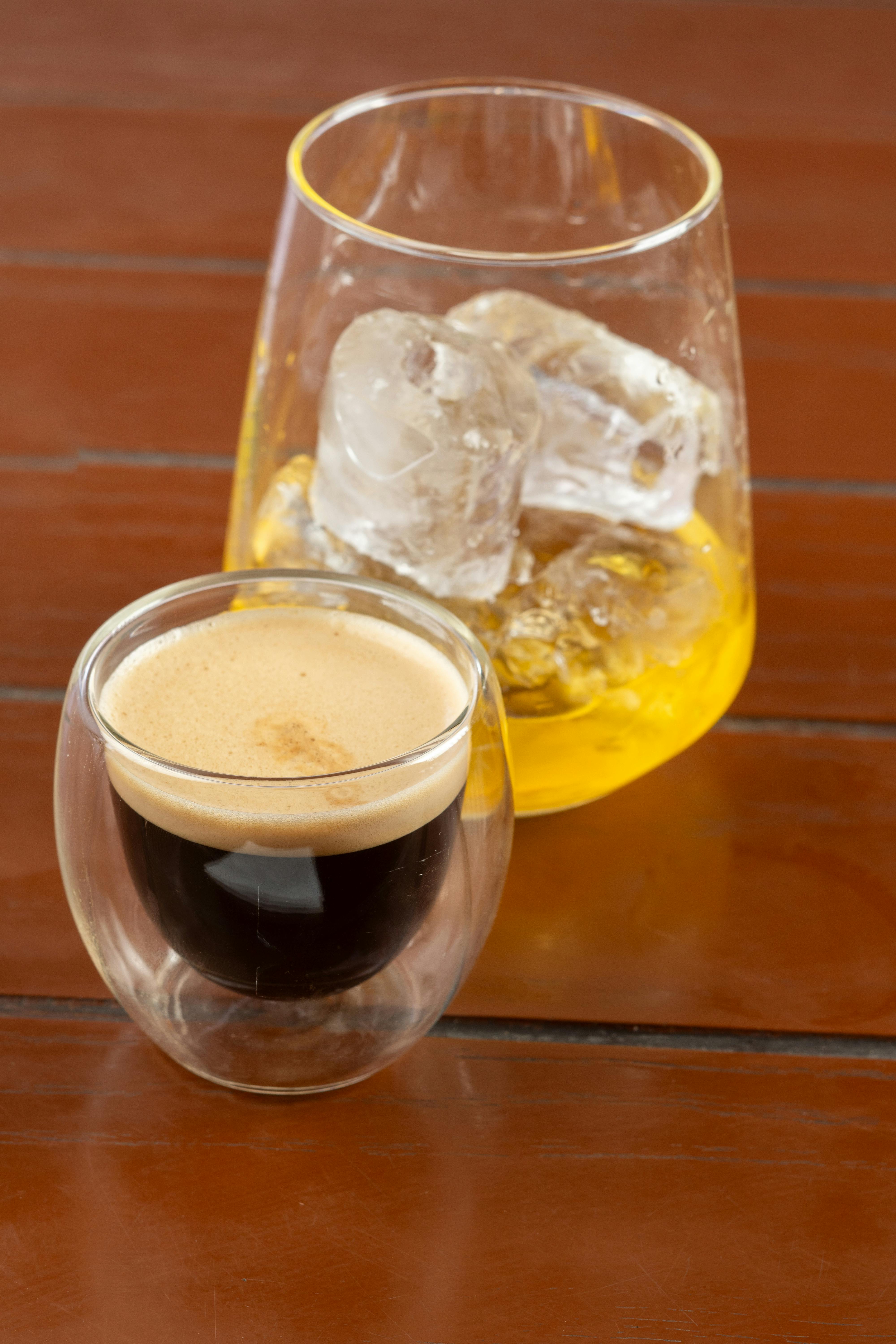 Close-up of freshly brewed espresso and whiskey on a wooden table, perfect for drink lovers.