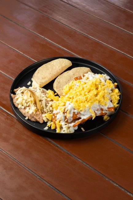A thick flour tortilla folded in half over a layer of mashed red beans, crumbled white cheese, and a drizzle of crema, cut open to show the filling.