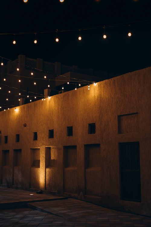 Free A warm-lit historic wall at night in Dubai capturing Middle Eastern architectural beauty. Stock Photo
