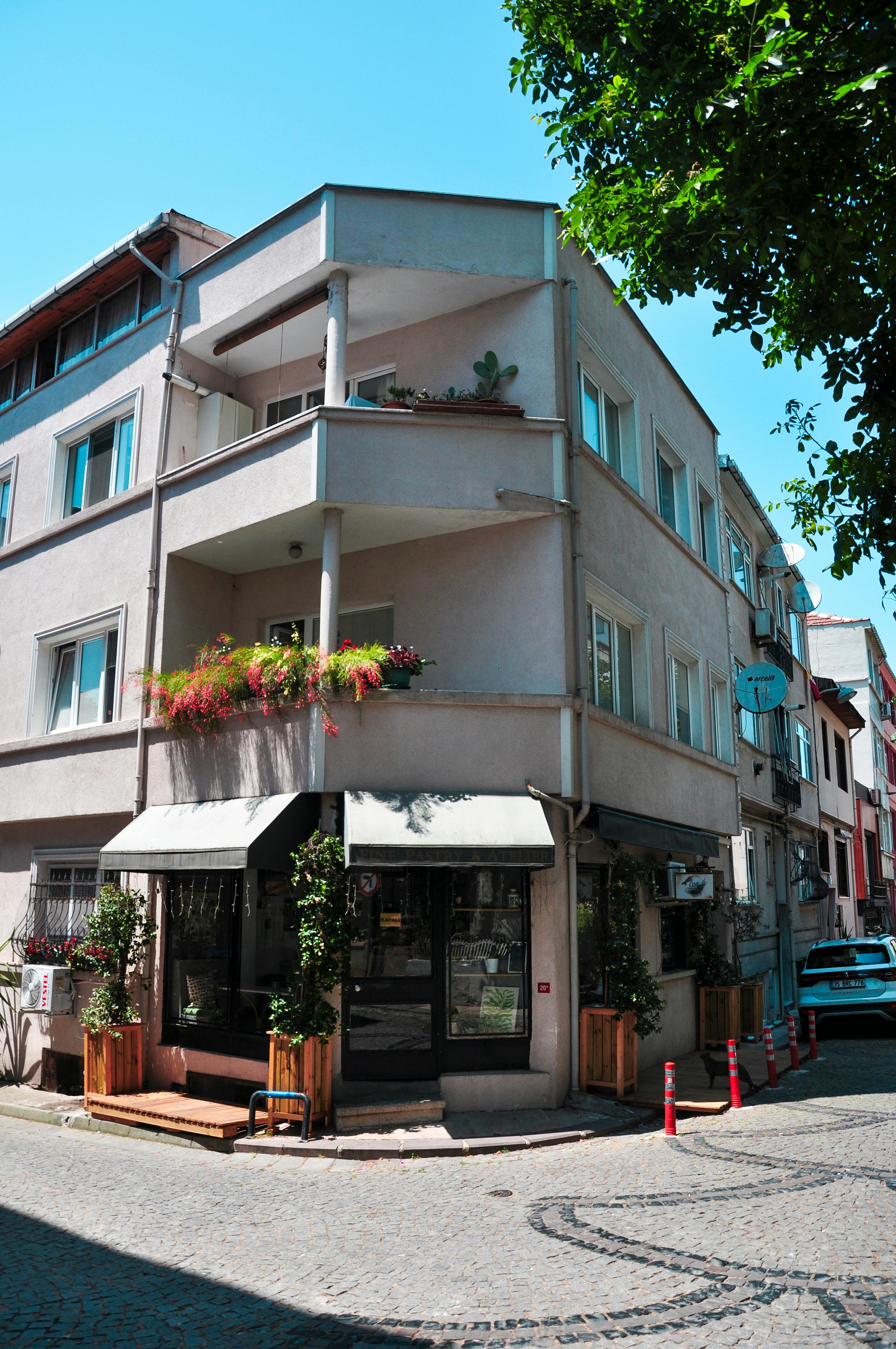 Free A cozy corner building with balconies, flowers, and a cafe on a sunny day. Stock Photo
