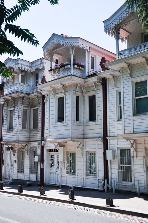 Free Charming traditional Ottoman-style wooden houses with ornate balconies and white facades on a sunny street. Stock Photo