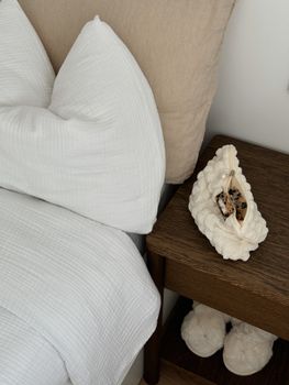 Stylish bedroom corner with fluffy pillows and wooden nightstand decor.