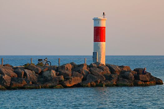 A calming scene of sunrise at Webster's lighthouse with rocks and a bicycle.