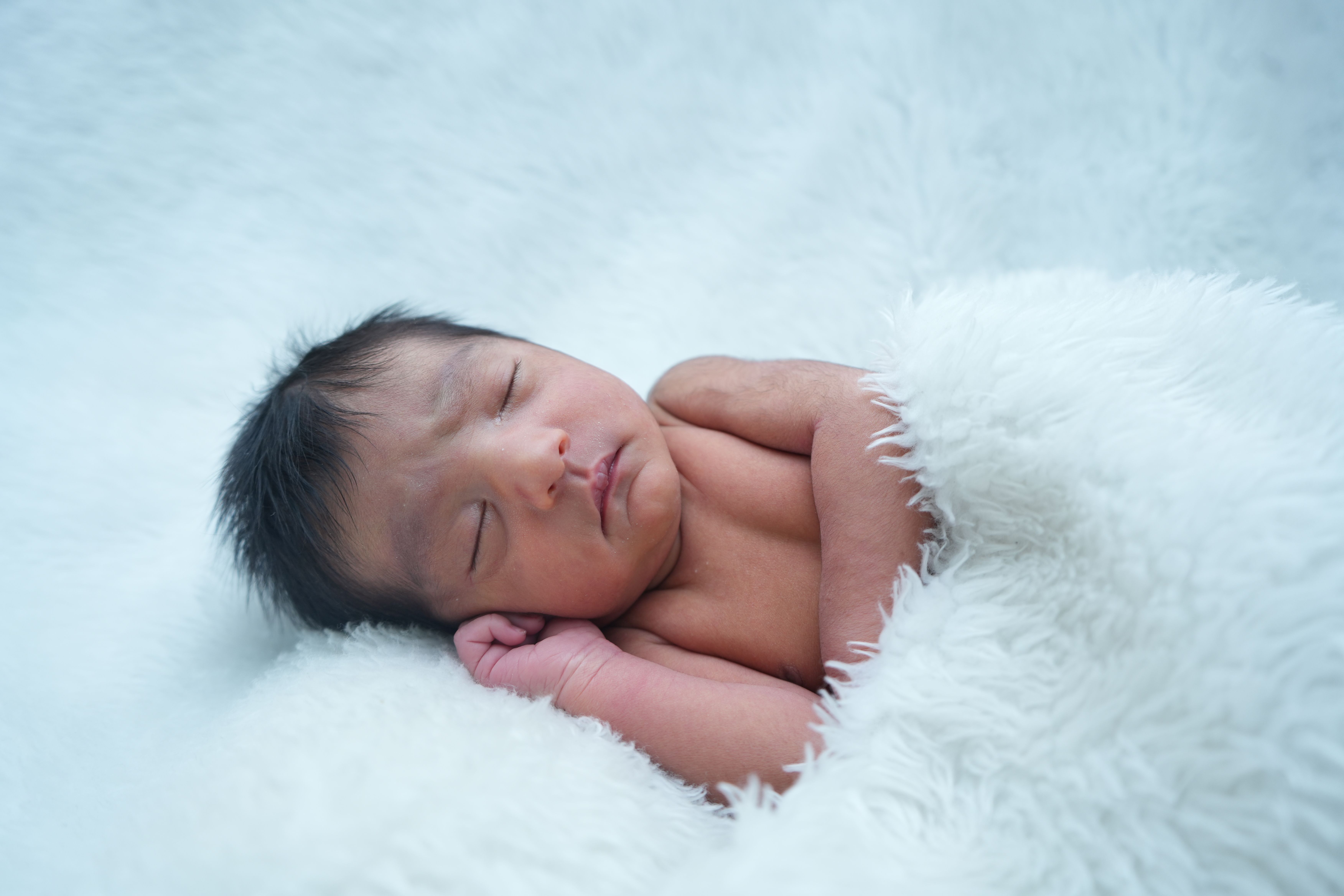 Mother gently holding newborn baby in hospital setting, showcasing warmth and love.