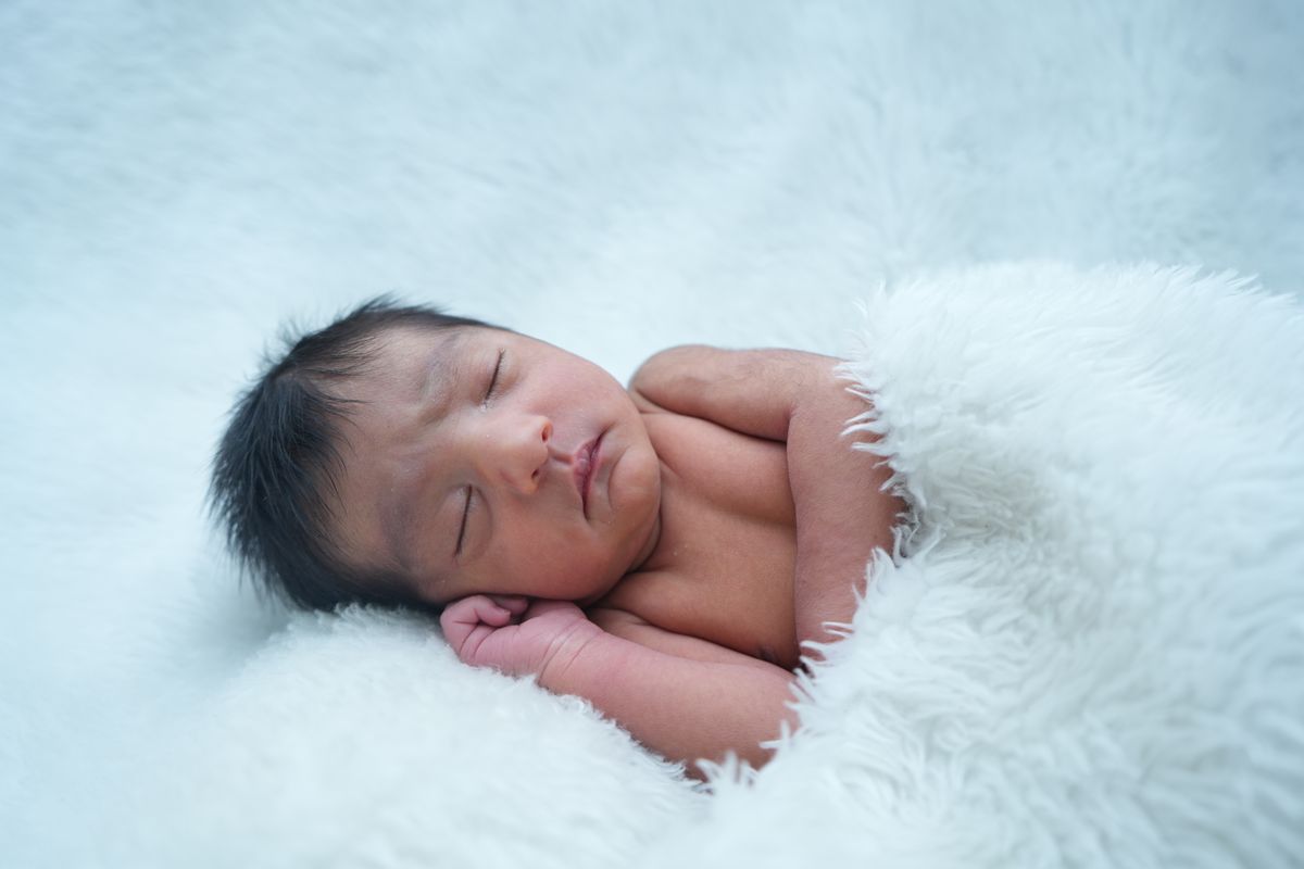 Newborn baby sleeping on a soft blanket for first birthday photoshoot ideas