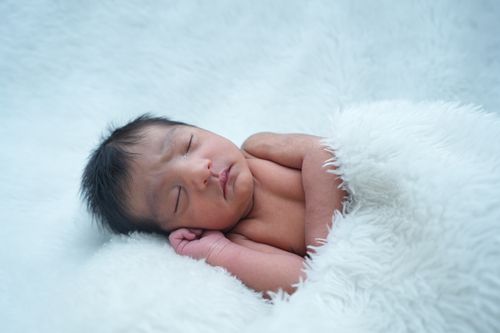 Free A serene newborn baby sleeping wrapped in a fluffy white blanket, evoking tranquility and innocence. Stock Photo
