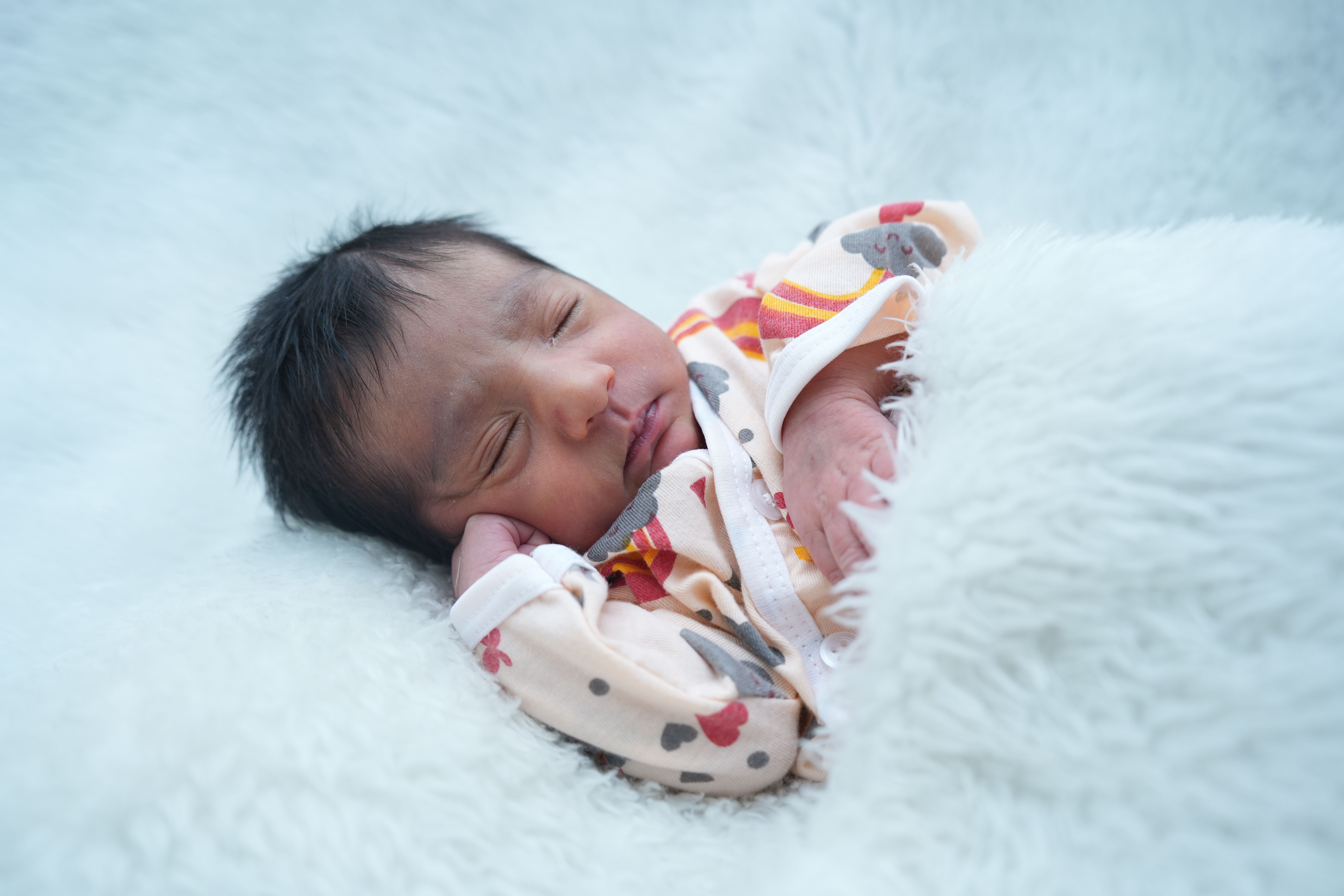 Mother gently holding newborn baby in hospital setting, showcasing warmth and love.