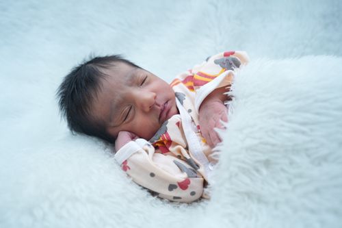 Free A serene scene of a newborn baby asleep on a fluffy white blanket, showcasing innocence and tranquility. Stock Photo