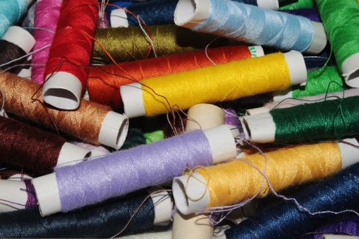 A vibrant collection of colorful sewing threads in spools, essential for tailoring and crafts.
