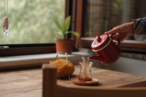 Free A warm indoor setting with tea being poured and yarn on a wooden table. Stock Photo