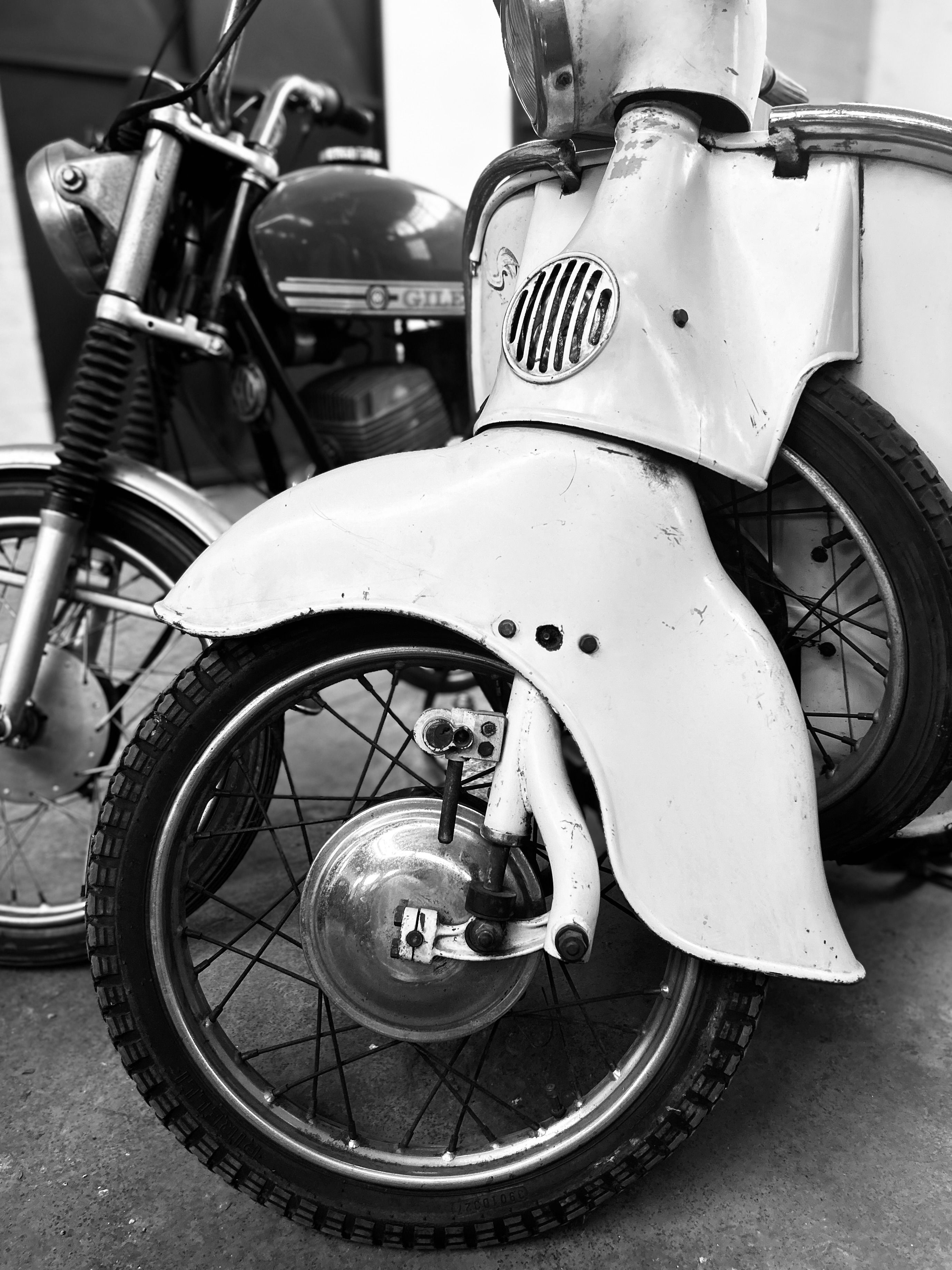 Detailed black and white image showcasing classic vintage motorcycles parked closely together.