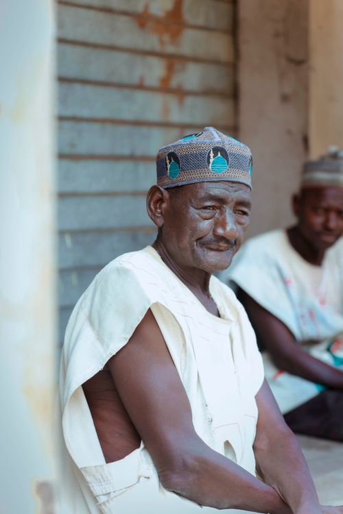 Free Two African men in traditional clothing sitting outside, captured with a warm and serene mood. Stock Photo