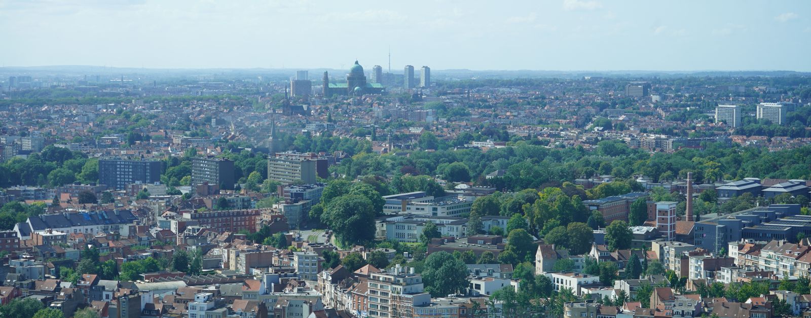 Aerial view of Brussels city with iconic landmarks and lush greenery.