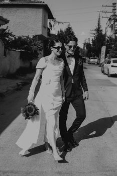 Stylish couple in black and white enjoying an outdoor wedding stroll.