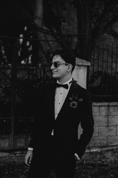 Stylish black and white portrait featuring a man in a tuxedo with sunglasses.