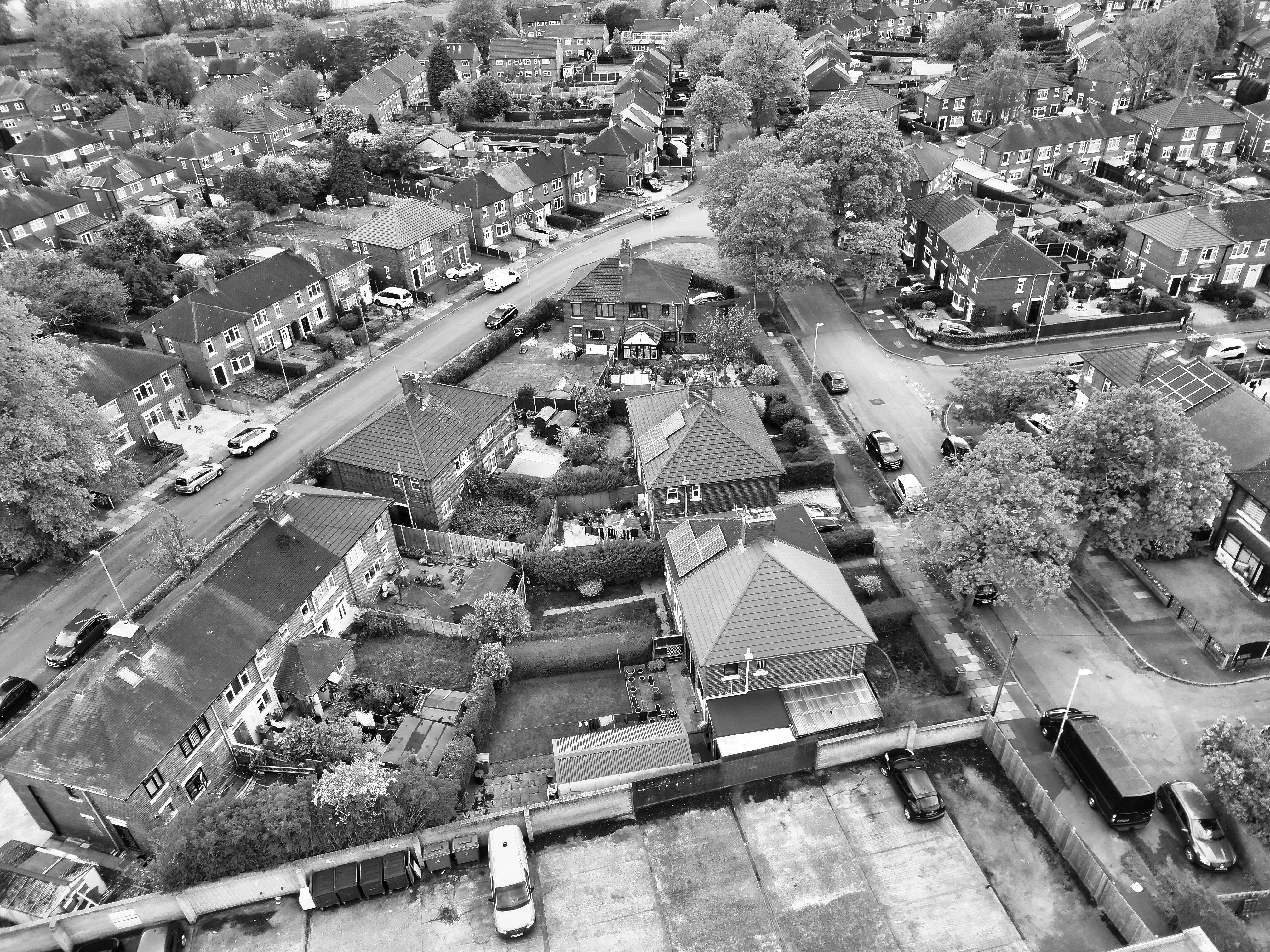 Aerial view of a suburban neighborhood in black and white, showcasing residential houses and streets.