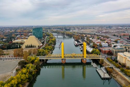Free Scenic aerial shot of the Tower Bridge in Sacramento surrounded by cityscape and river. Stock Photo
