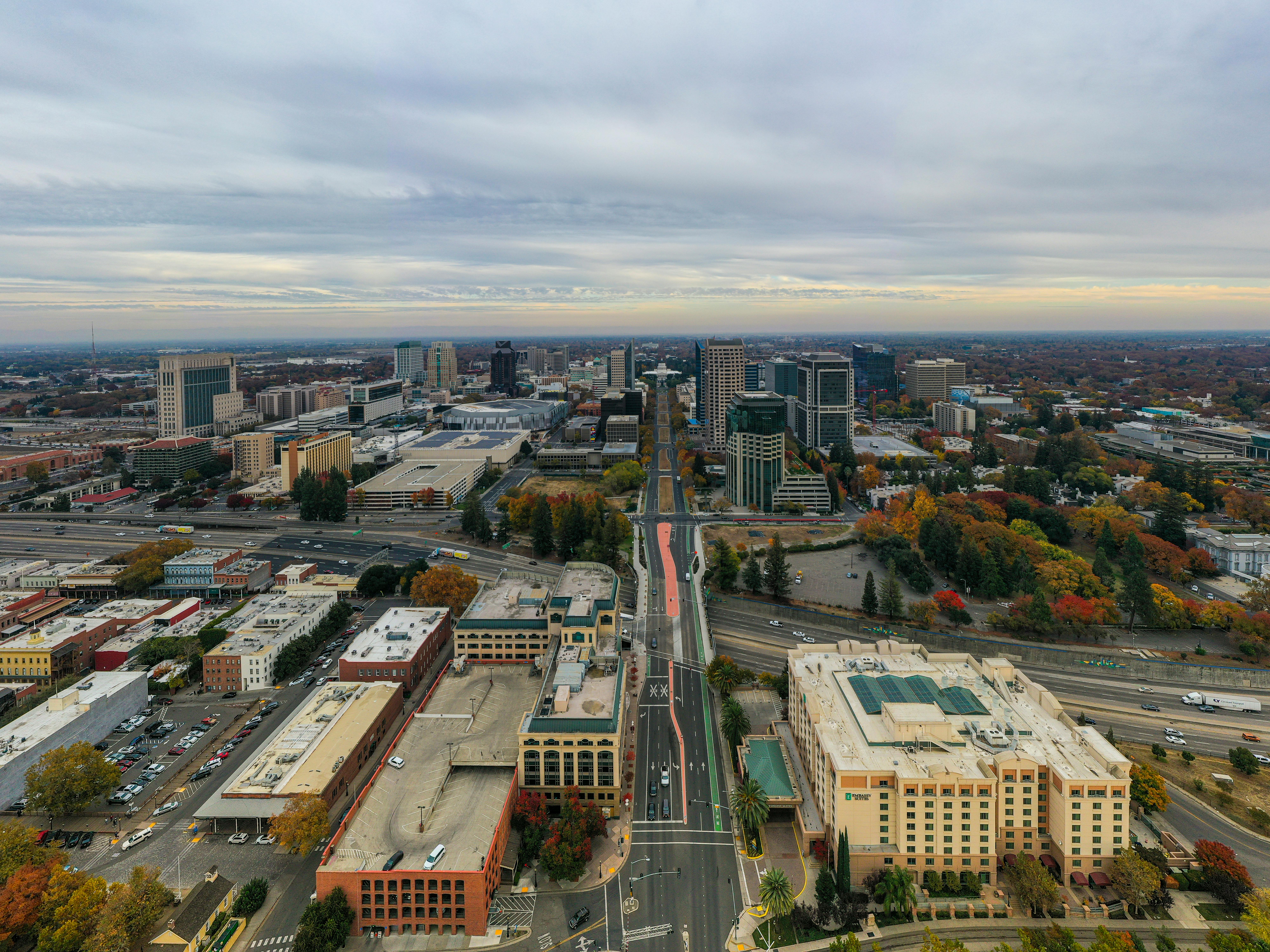 Aerial view of Sacramento cityscape with autumn colors and a cloudy sky.