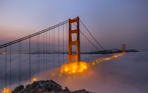 Free A breathtaking view of the Golden Gate Bridge engulfed in fog during twilight, creating a magical atmosphere. Stock Photo