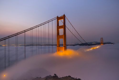 Free Golden Gate Bridge partially covered by evening fog, captured at twilight showcasing its iconic architecture. Stock Photo