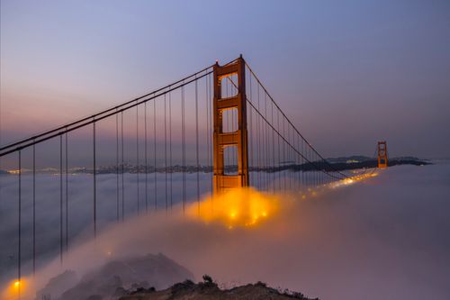 Free A misty evening view of the Golden Gate Bridge shrouded in fog, captured at dusk. Stock Photo