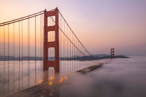 Free Aerial view of the Golden Gate Bridge enveloped in fog at sunrise. Stock Photo