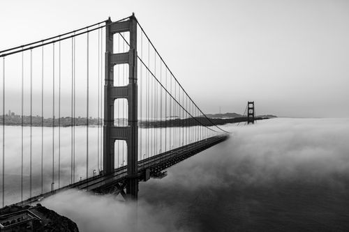 Free Dramatic black and white image of Golden Gate Bridge enveloped in fog. Iconic landmark. Stock Photo