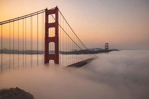 Free A stunning view of the Golden Gate Bridge partially hidden by morning fog, capturing a serene sunrise. Stock Photo