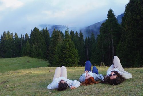 Free Three people relaxing on grassy field amidst Giresun's tranquil forest scenery. Stock Photo