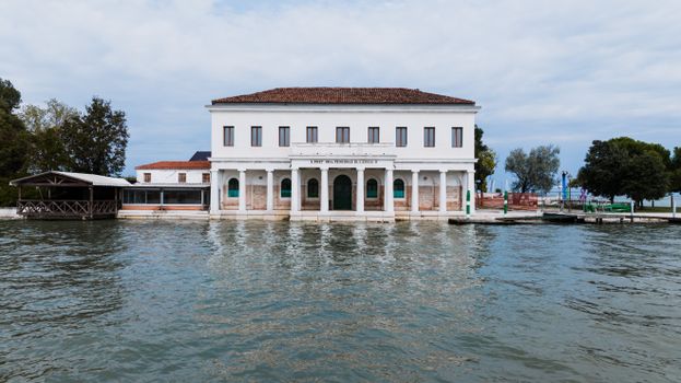 Elegant neoclassical building with columns by the water in Venice, showcasing Italian architecture.