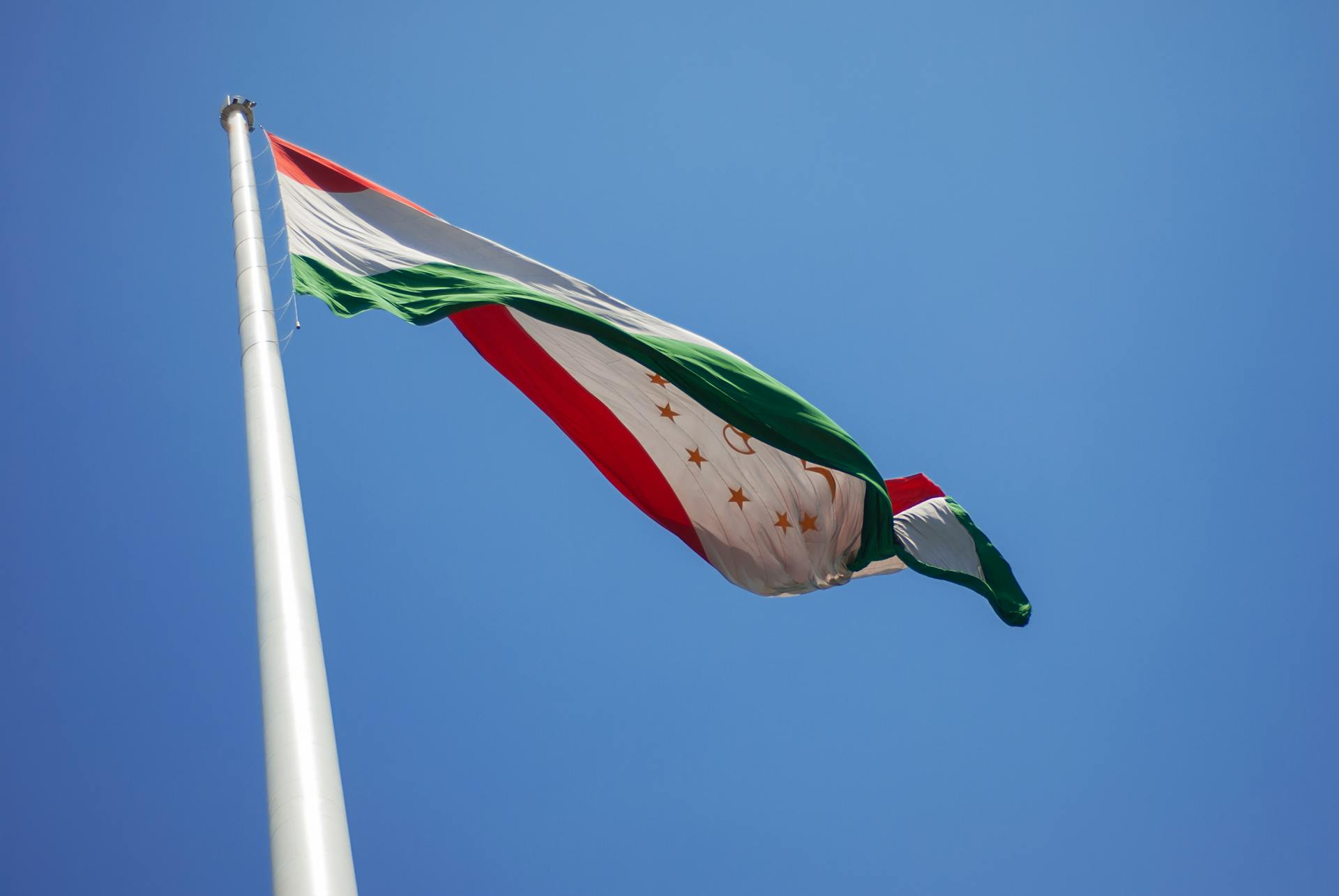 Tajikistan national flag waving against a clear blue sky, symbolizing national pride.