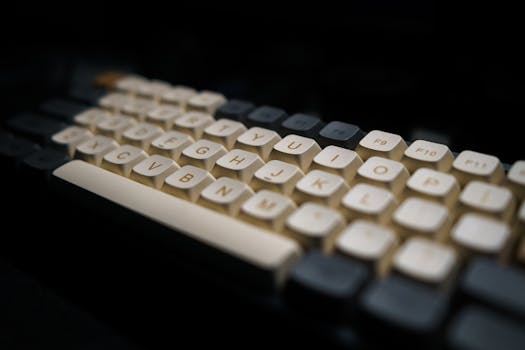 Close-up of a modern mechanical keyboard with white keycaps in a dark setting.