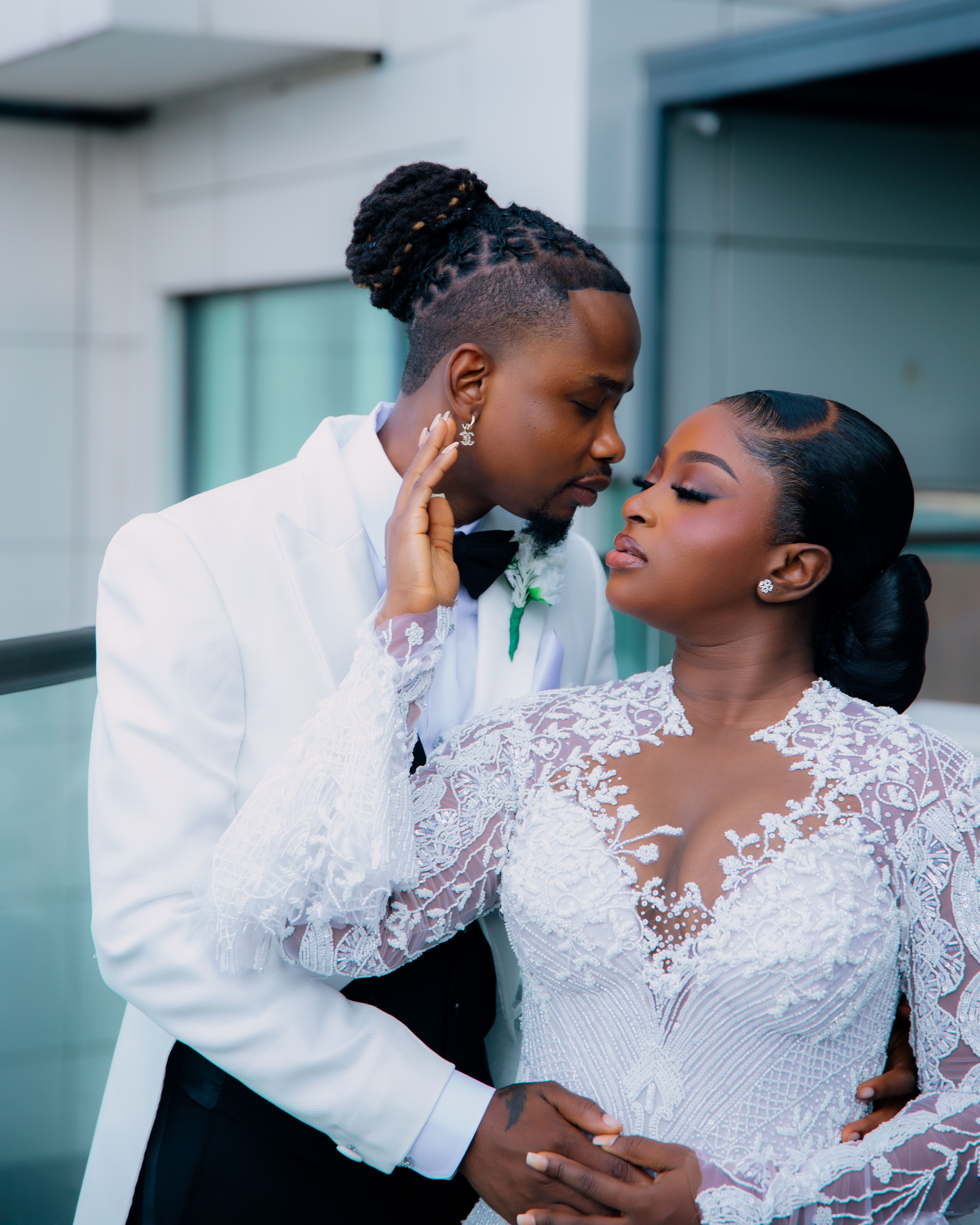 Romantic portrait of a wedding couple embracing in elegant attire, outdoors.
