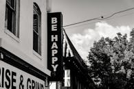 一张写着“快乐”的单色标牌图像，位于建筑物的角落