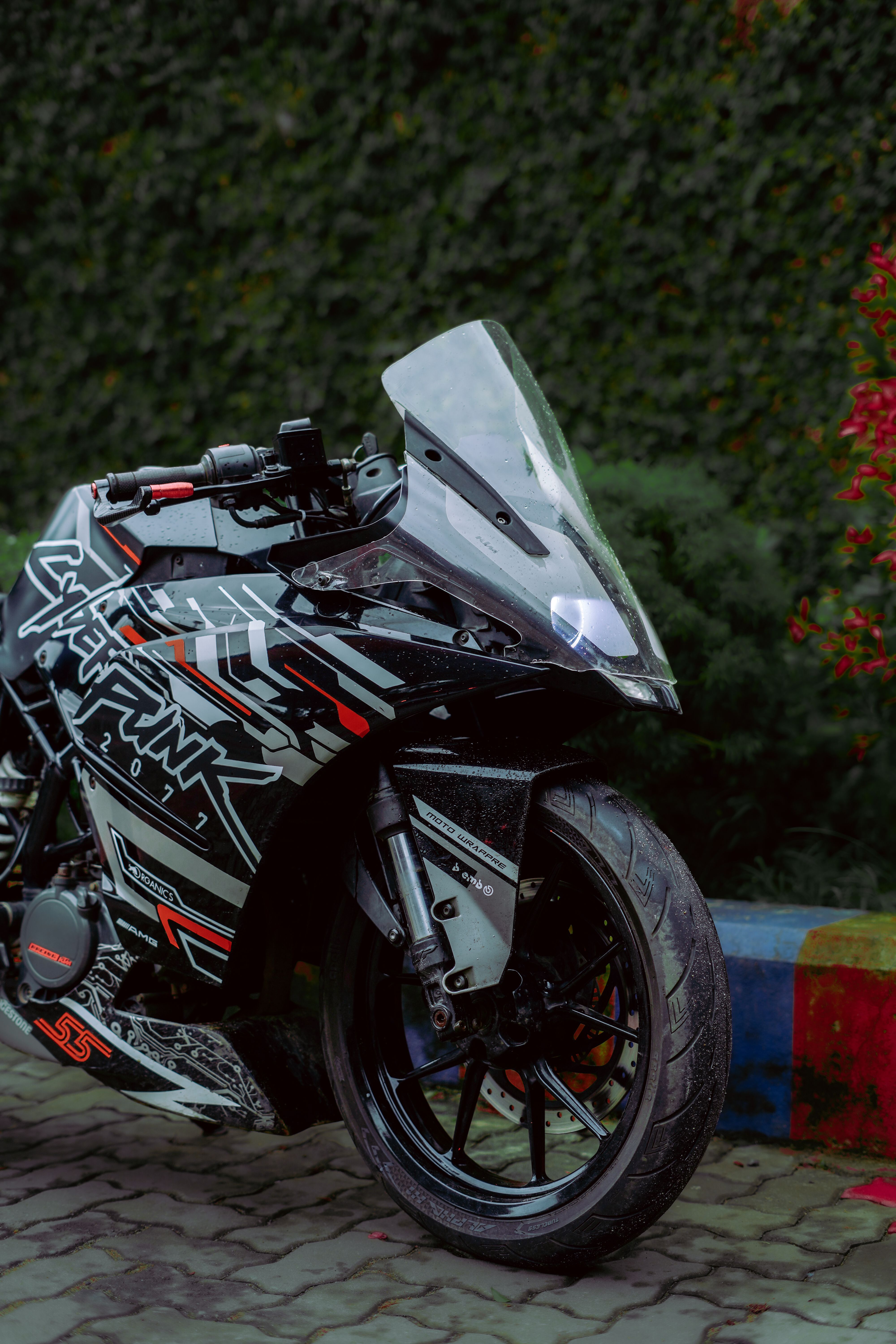 Black and sleek motorcycle with cyberpunk graphics parked on vibrant urban street.
