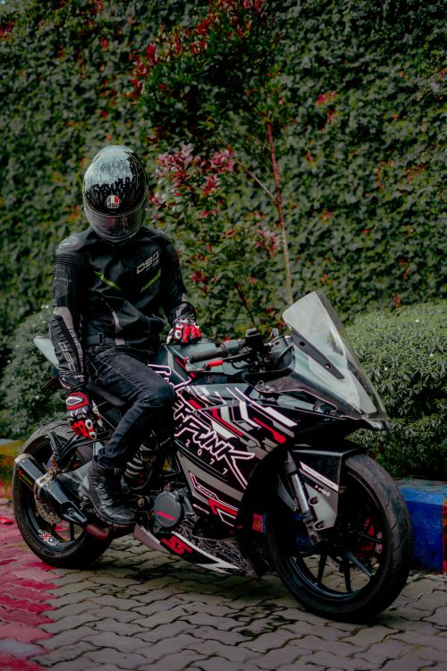 Free Motorcyclist in gear posing on a sports bike outdoors by greenery. Stock Photo
