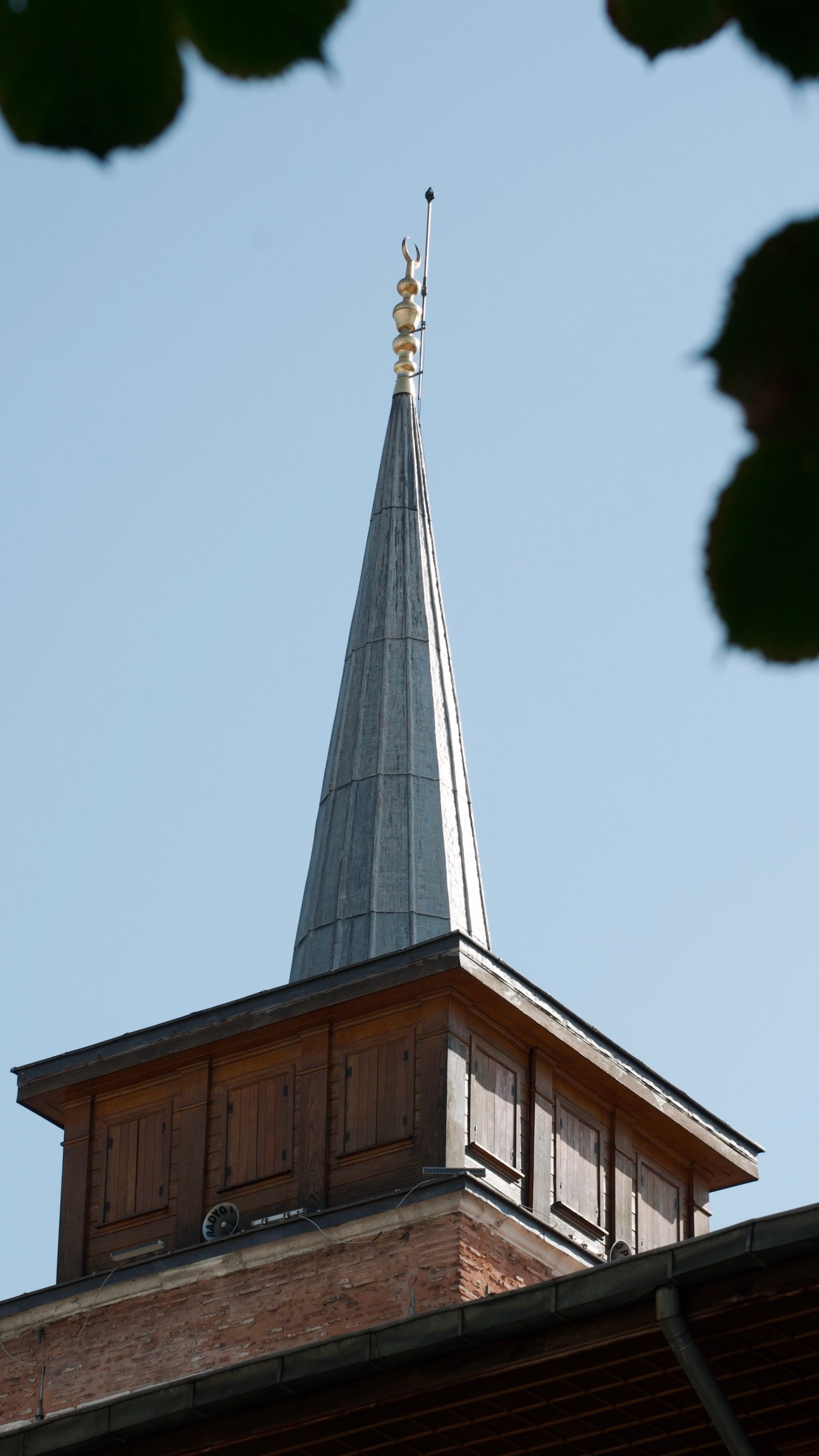A historic architectural steeple against a clear blue sky.