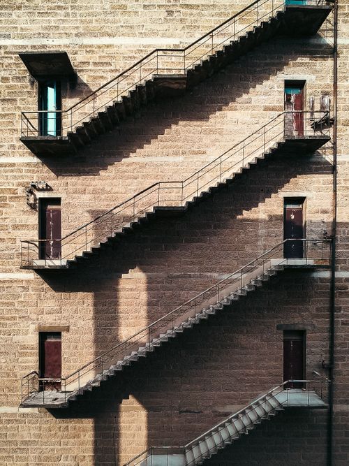 Free Detailed view of a symmetrical metal fire escape staircase against a vintage brick wall. Stock Photo