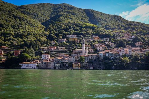 Free Picturesque Italian village with colorful houses by a serene green lake. Stock Photo