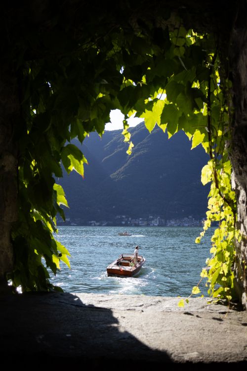 Free A serene wooden boat on a picturesque lake framed by lush greenery. Stock Photo