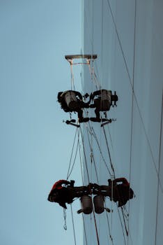 摩天大楼的窗户清洁工用绳子悬吊着，在玻璃上工作