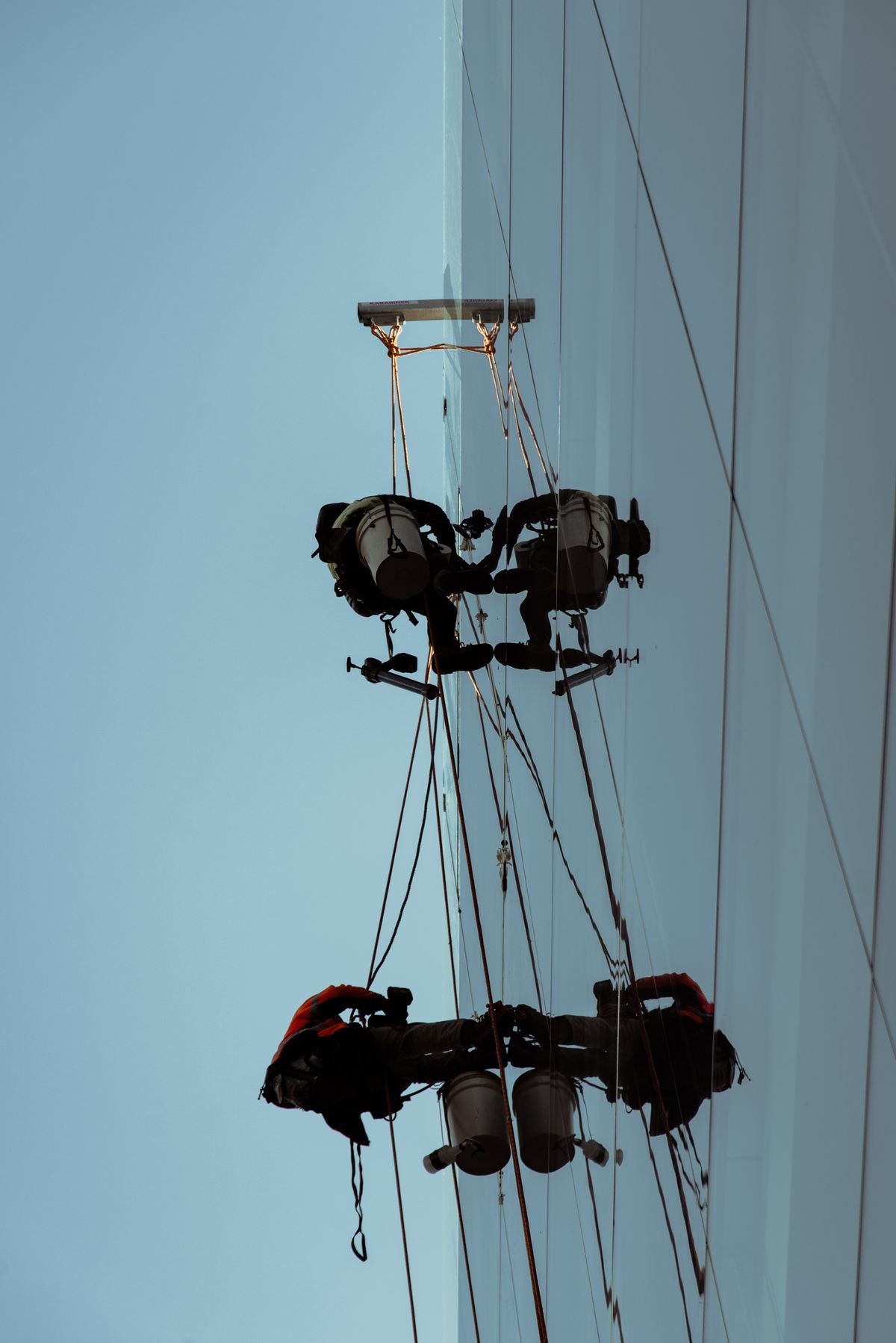 Rope access window cleaning team suspended on a glass tower