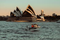 日落时分，一艘船在悉尼歌剧院的港口航行
