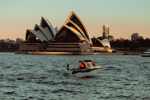 日落时分，一艘船在悉尼歌剧院的港口航行